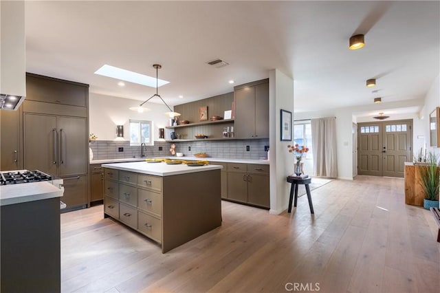 kitchen with a skylight, a sink, decorative backsplash, and open shelves