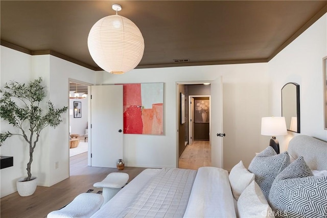 bedroom featuring visible vents, wood finished floors, and ornamental molding