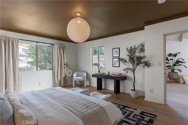 bedroom featuring multiple windows, crown molding, baseboards, and wood finished floors