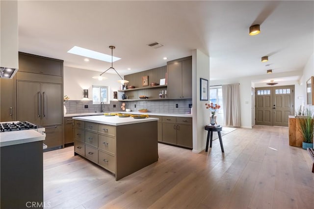 kitchen featuring a skylight, decorative backsplash, open shelves, and a sink