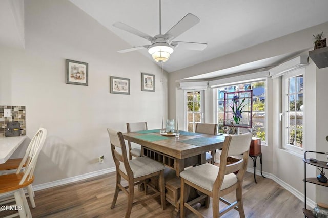 dining room featuring lofted ceiling, light wood-style floors, baseboards, and a ceiling fan