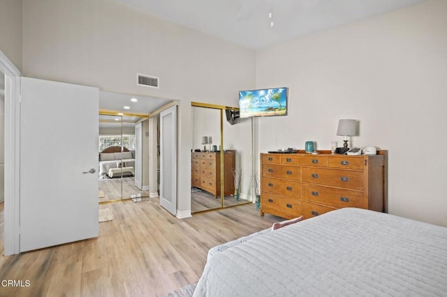 bedroom with recessed lighting, wood finished floors, visible vents, baseboards, and multiple closets