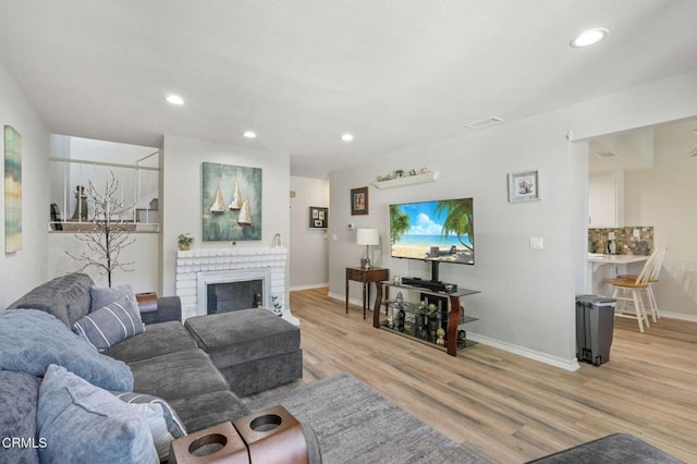 living room featuring light wood-type flooring, a fireplace, and recessed lighting