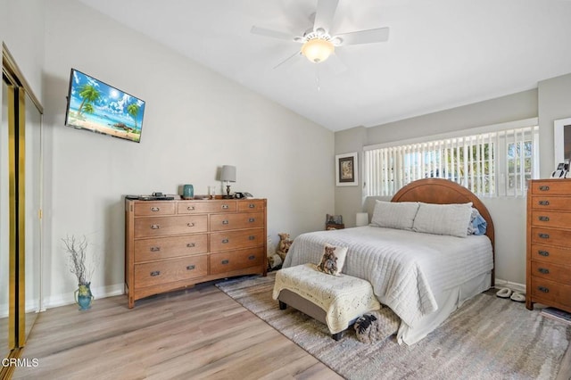 bedroom featuring light wood finished floors, lofted ceiling, a closet, ceiling fan, and baseboards