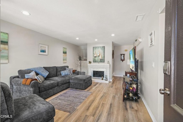 living area with light wood finished floors, visible vents, baseboards, a fireplace, and recessed lighting