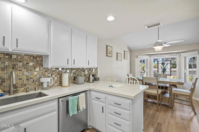 kitchen featuring visible vents, decorative backsplash, a sink, dishwasher, and a peninsula