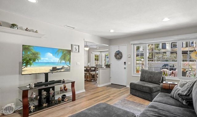 living room with recessed lighting, visible vents, baseboards, and wood finished floors