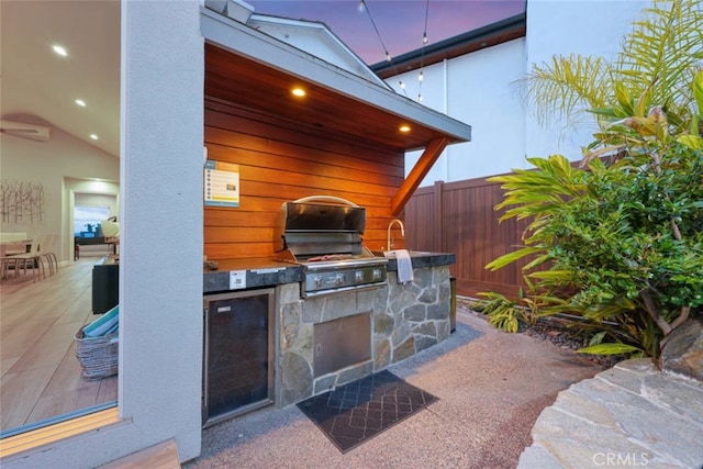 view of patio with a grill, fence, and an outdoor kitchen