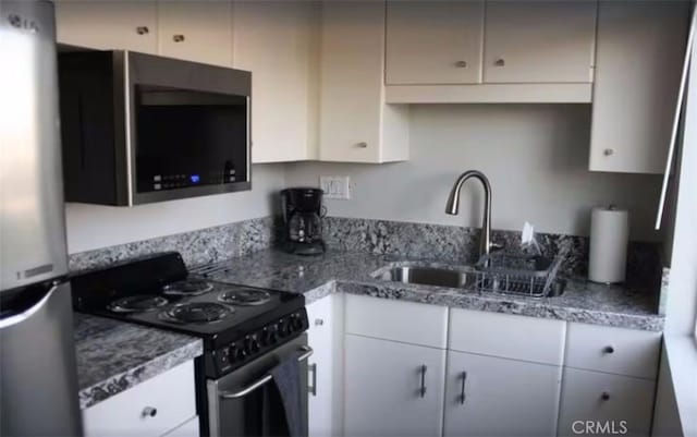 kitchen with stainless steel appliances, a sink, and white cabinets