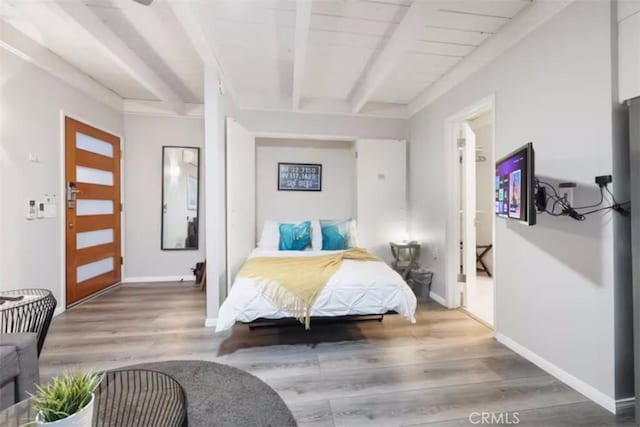 bedroom featuring baseboards, beamed ceiling, and wood finished floors