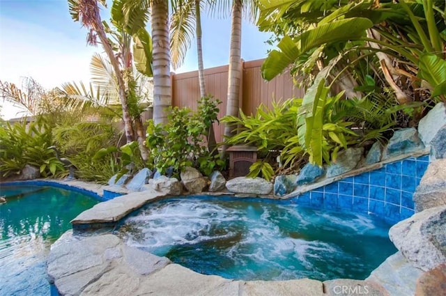 view of swimming pool with a fenced in pool, fence, and an in ground hot tub