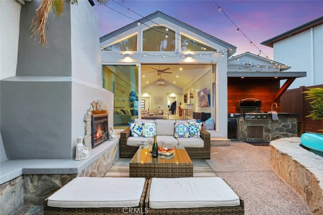 view of patio featuring an outdoor living space with a fireplace, fence, grilling area, and exterior kitchen