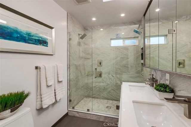 full bathroom with a marble finish shower, a sink, and toilet