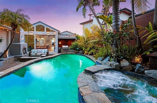 pool at dusk featuring an outdoor pool, a patio area, a jacuzzi, and an outdoor hangout area