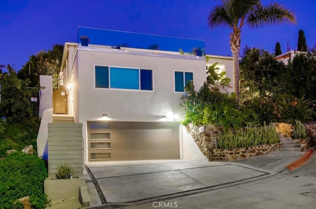 view of front of home featuring an attached garage, stairs, concrete driveway, and stucco siding