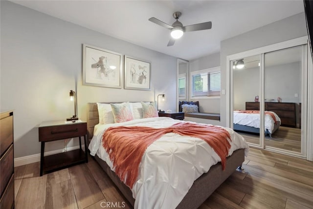 bedroom featuring a closet, wood finished floors, a ceiling fan, and baseboards