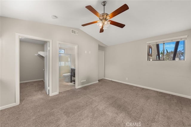 unfurnished bedroom with carpet floors, a walk in closet, lofted ceiling, a closet, and visible vents