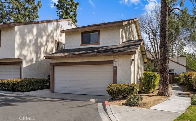 view of front of house with a garage, a shingled roof, concrete driveway, and stucco siding