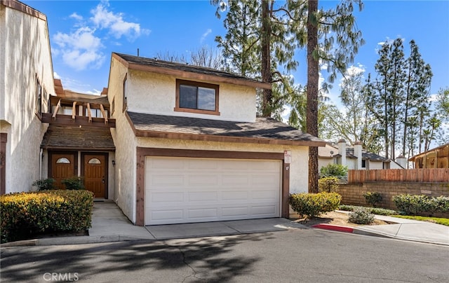 view of front of home with an attached garage, fence, driveway, roof with shingles, and stucco siding