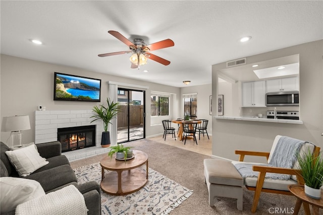 living area with carpet, a brick fireplace, visible vents, and recessed lighting