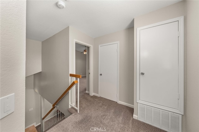 corridor with visible vents, carpet floors, an upstairs landing, and baseboards