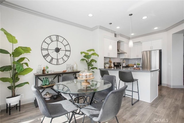 dining room featuring light wood finished floors, recessed lighting, crown molding, and baseboards