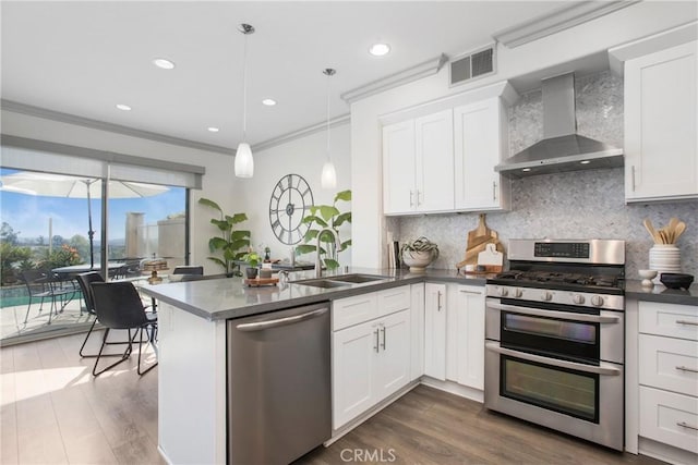 kitchen with visible vents, appliances with stainless steel finishes, white cabinetry, wall chimney exhaust hood, and a sink