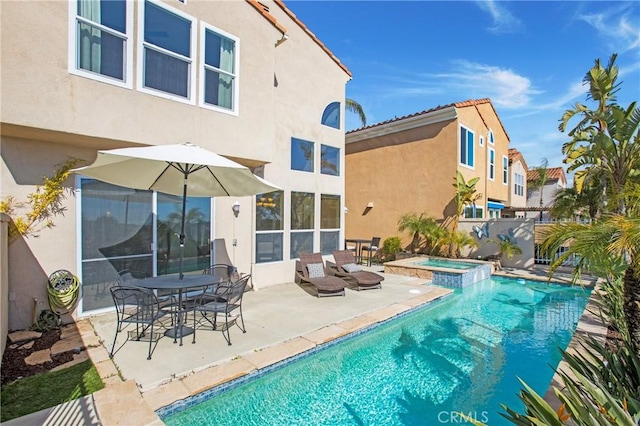 rear view of house featuring stucco siding, a patio, a pool with connected hot tub, and fence