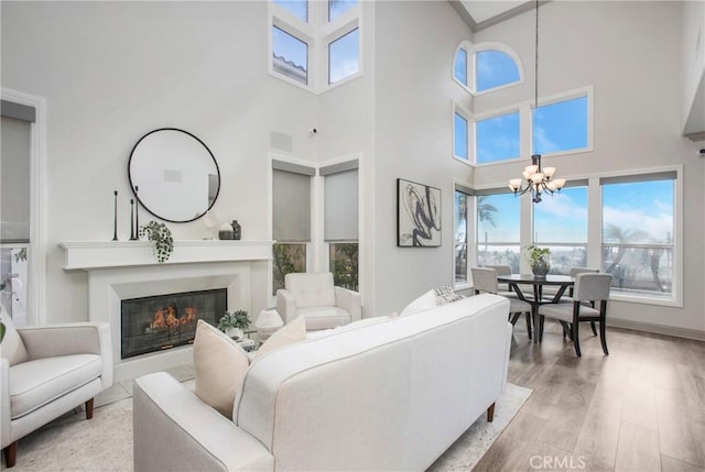 living area with a notable chandelier, light wood-style floors, visible vents, and a glass covered fireplace