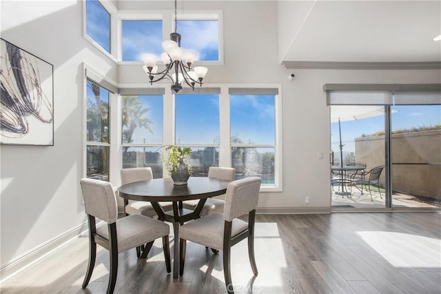 dining room featuring an inviting chandelier, wood finished floors, baseboards, and a towering ceiling