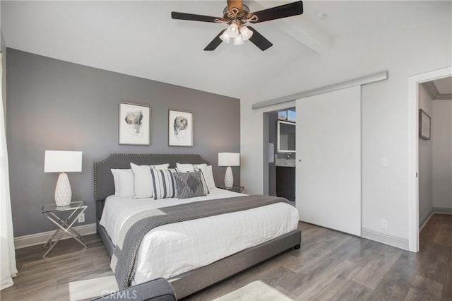 bedroom featuring a closet, baseboards, wood finished floors, and vaulted ceiling with beams