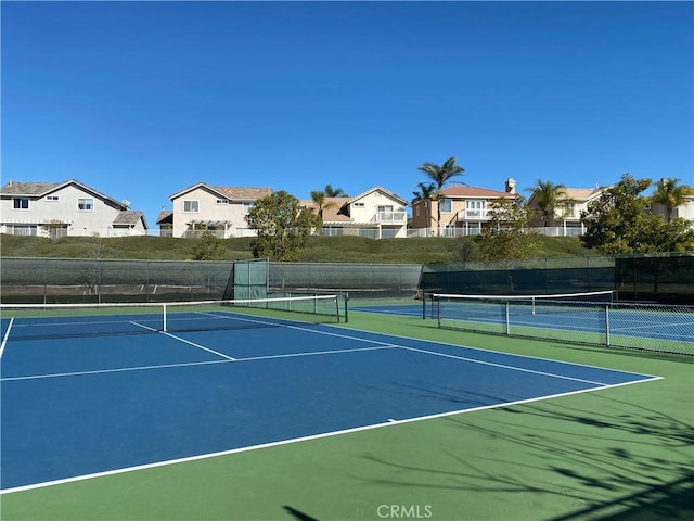 view of tennis court with a residential view, community basketball court, and fence