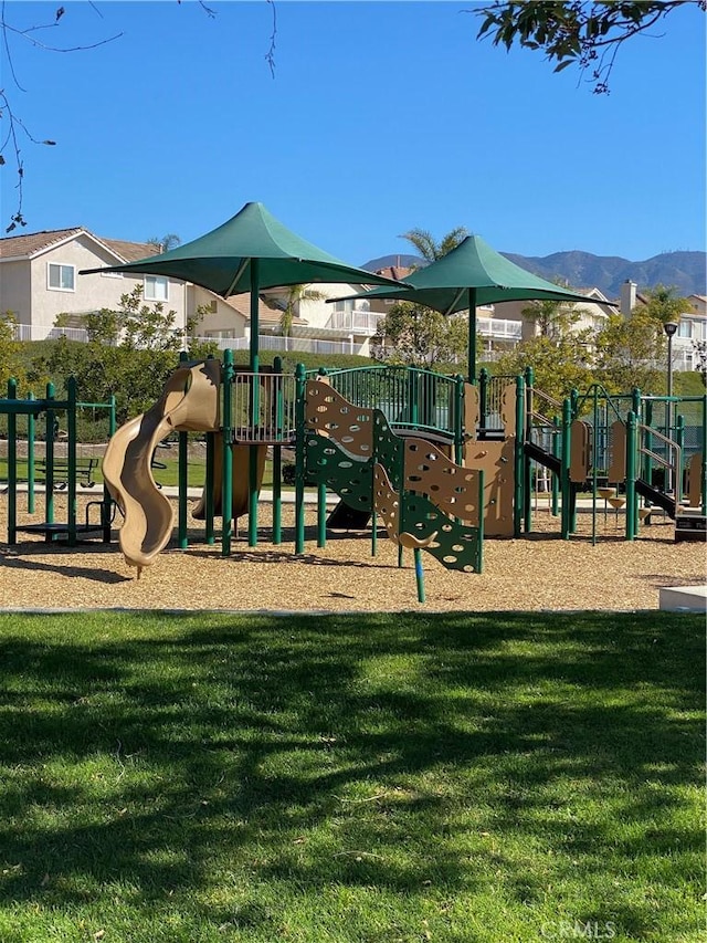 communal playground featuring a mountain view and a yard