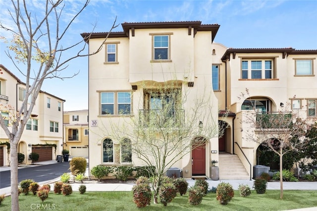 view of front of property featuring driveway, an attached garage, a tiled roof, and stucco siding