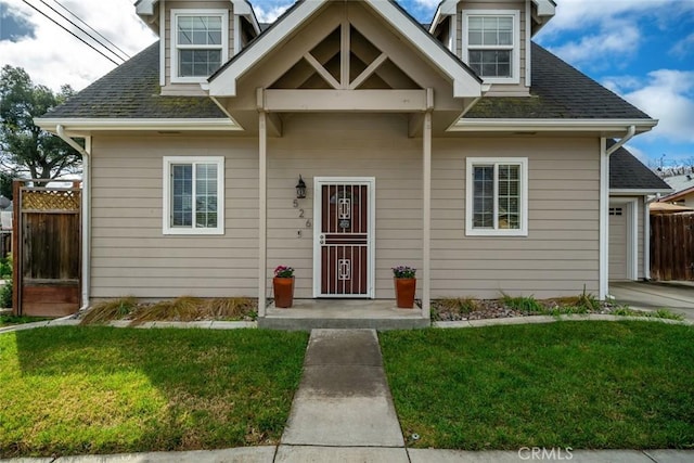 view of front of property featuring a shingled roof, a front yard, fence, and a garage