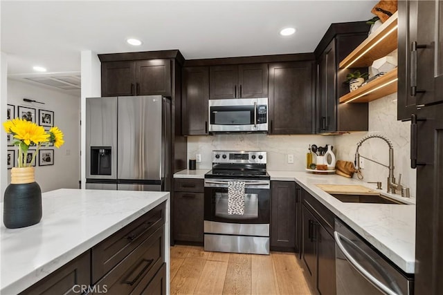 kitchen with stainless steel appliances, light wood-style floors, a sink, and dark brown cabinets