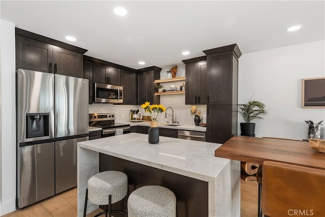 kitchen featuring open shelves, light wood-style flooring, a kitchen bar, and stainless steel appliances