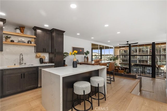 kitchen with stainless steel dishwasher, a sink, light wood-style flooring, and decorative backsplash