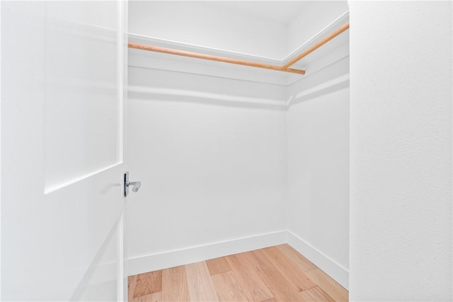 walk in closet with light wood-style floors