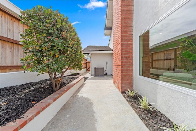 view of property exterior featuring central AC, fence, a patio, and stucco siding