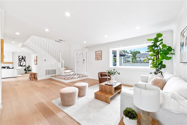 living room featuring baseboards, visible vents, stairs, light wood-type flooring, and recessed lighting