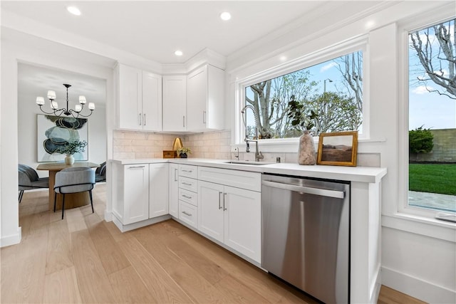 kitchen with dishwasher, light countertops, backsplash, and a sink