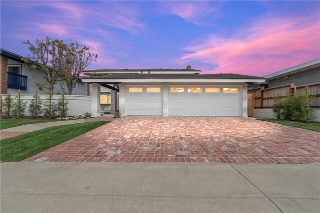 view of front of home with brick siding, decorative driveway, and an attached garage