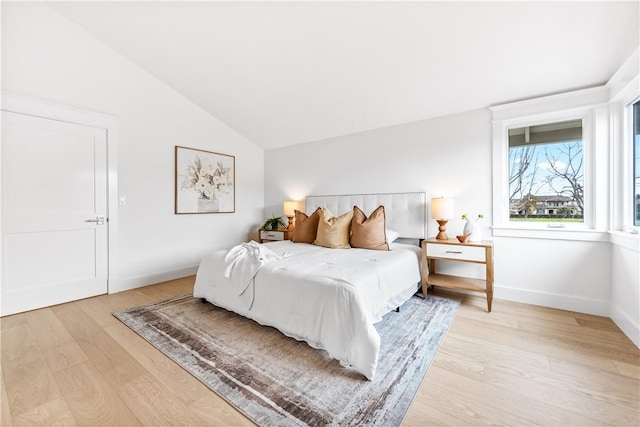 bedroom featuring baseboards, vaulted ceiling, and light wood finished floors