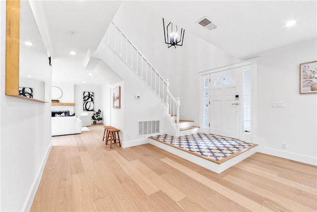 foyer featuring stairway, baseboards, visible vents, and wood finished floors