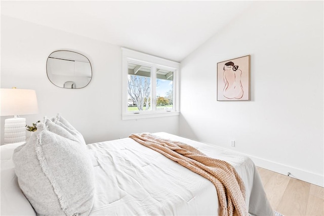 bedroom with vaulted ceiling, baseboards, and wood finished floors