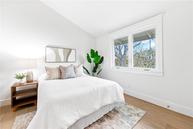 bedroom with lofted ceiling, baseboards, and wood finished floors