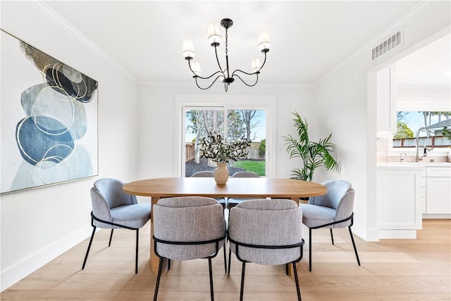 dining area featuring light wood-style flooring, visible vents, a chandelier, and crown molding