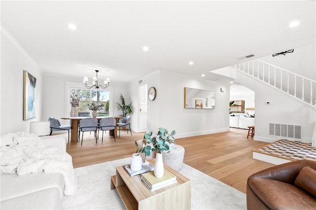 living area with light wood-type flooring, stairway, visible vents, and crown molding