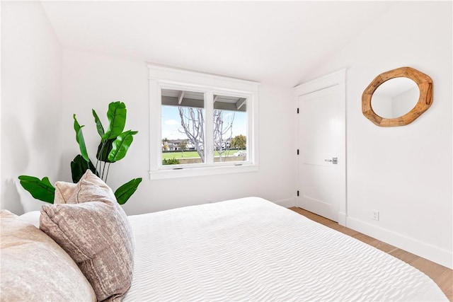 bedroom with lofted ceiling, wood finished floors, and baseboards